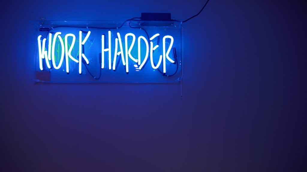 Neon sign saying Work Harder - among the career tips listed as learned from the first job experiences of those interviewed for this article