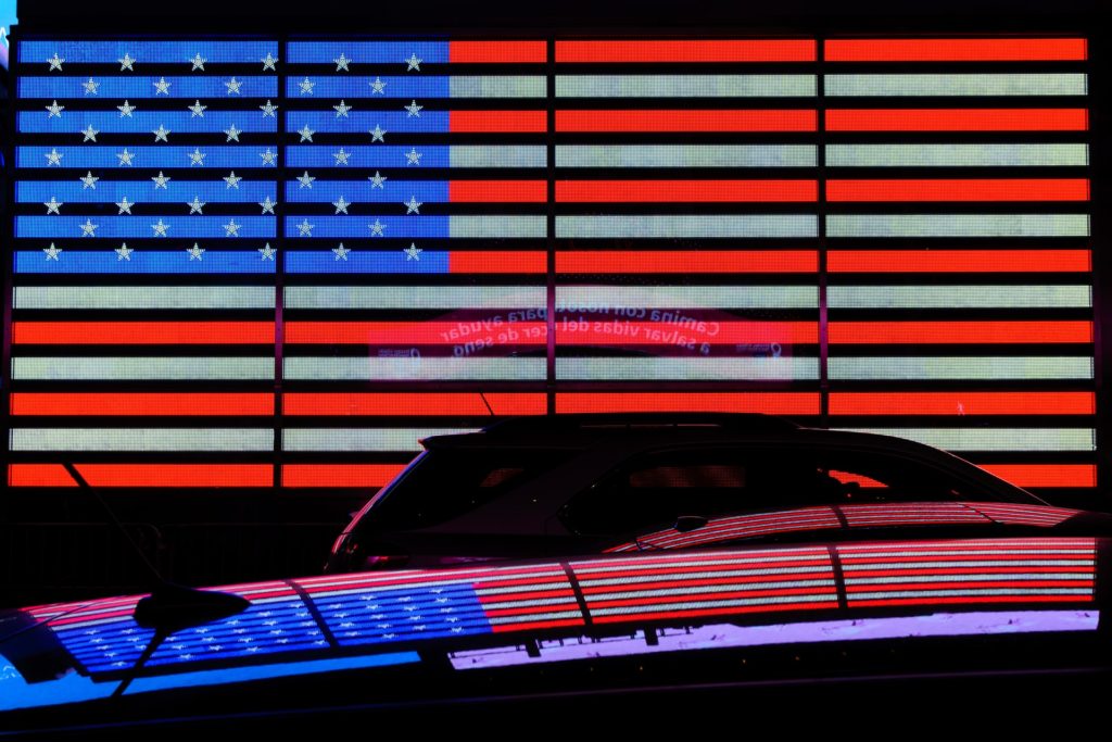 Cause marketing & brand trust: image of a neon U.S. flag and its reflection mirrored on the black silhouette of a car in the foreground