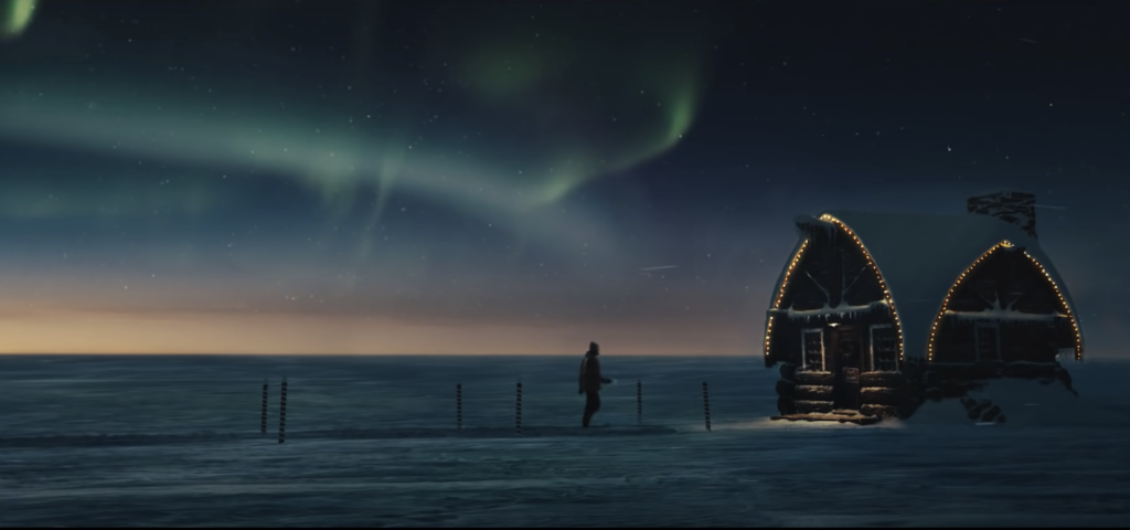 silhouette of man walking toward santa's home in the north pole with the northern lights in the sky in the background