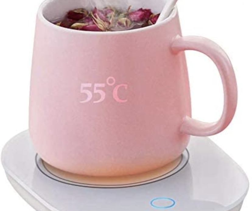 pink coffee mug resting on a flat mug warmer with tea inside of it, an item on the ultimate gift guide for marketers and copywriters