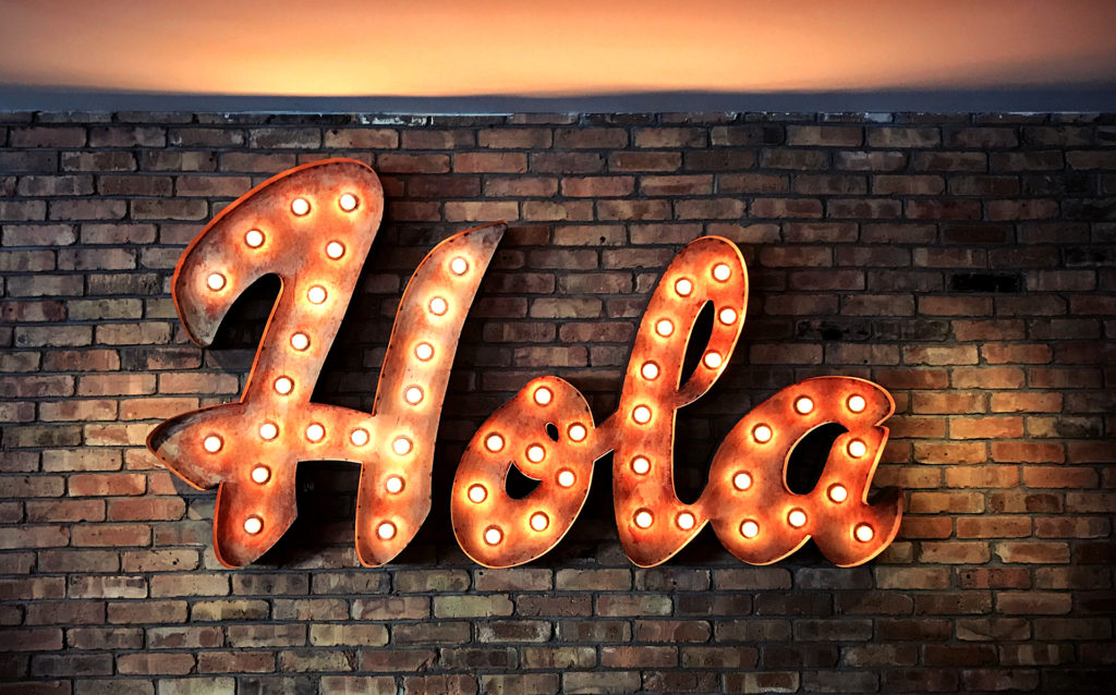 neon sign that says Hola - say hello the right way to new customers and users with this complete guide to onboarding