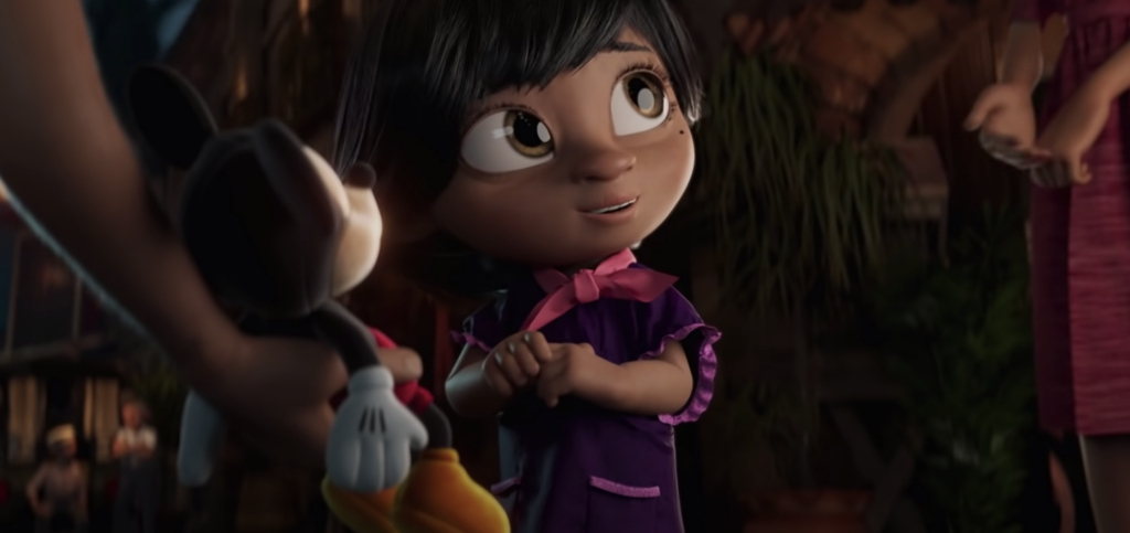 a young brown girl being handed a Mickey Mouse doll as a gift by her parents; a still from the Disney 2020 holiday marketing campaign