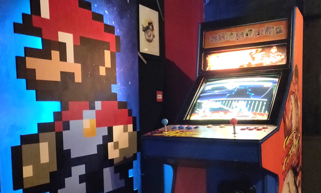 classic video game arcade machine with pixelated image of Mario from Super Mario Brothers. painted on the wall in the background - an example of nostalgia marketing,  which was the biggest trend of 2020 during the pandemic and beyond