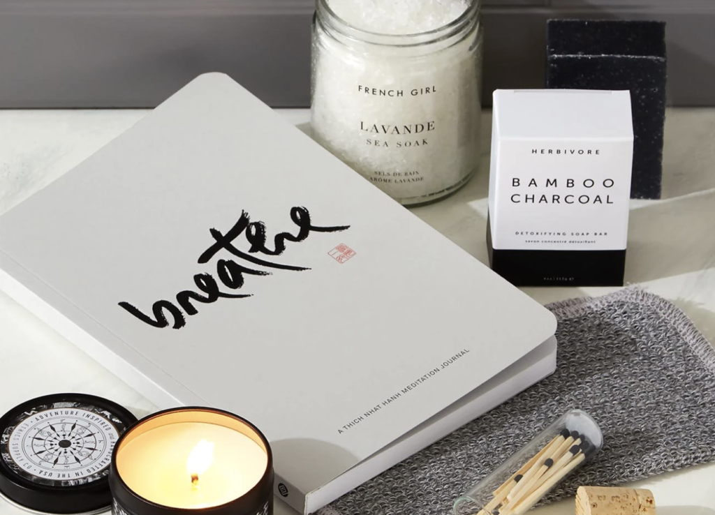 a notebook that says breathe on it next to a candle, box that says bamboo charcoal on it, and another jar of sea soak - a relaxing, pampering holiday gift for professionals, marketers and copywriters