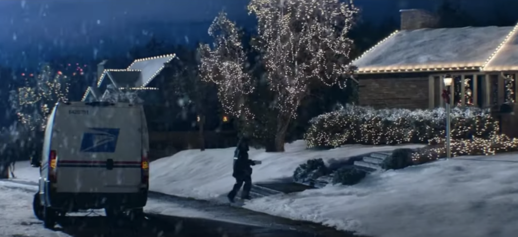 a USPS truck parked outside a home decorated with Christmas lights with snow everywhere. a still from the USPS holiday marketing campaign ad 2020