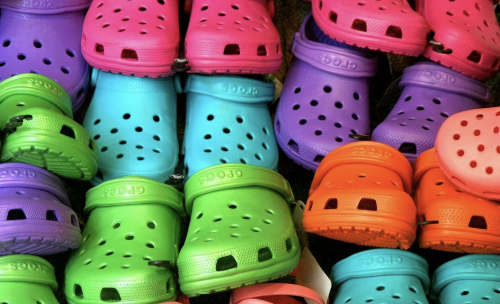 multicolored crocs shoes stacked in. rows - the crocs brand experienced success in 2020 due to innovative coronavirus marketing strategy and gen-z tiktok influencers